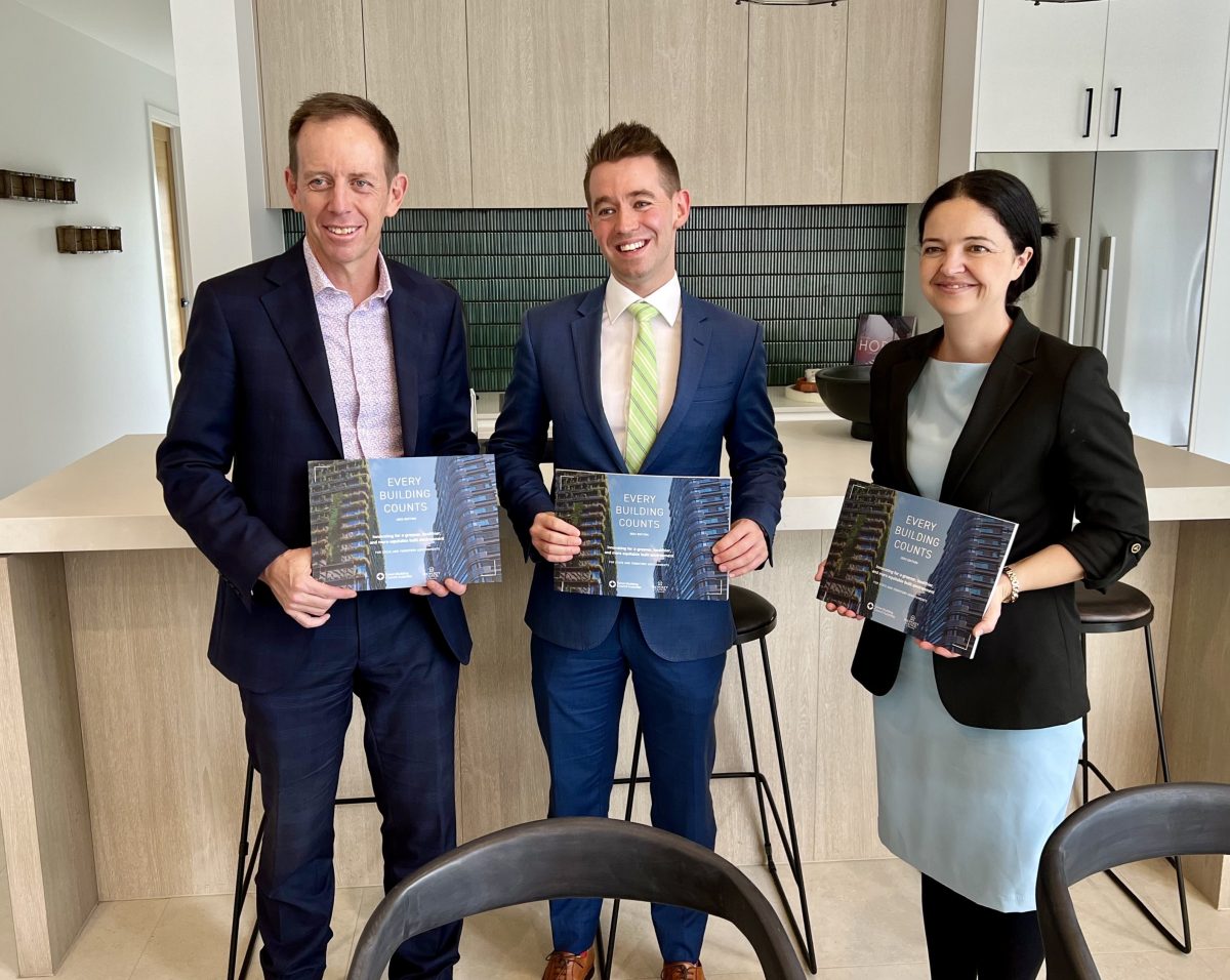 three people holding brochures in a kitchen